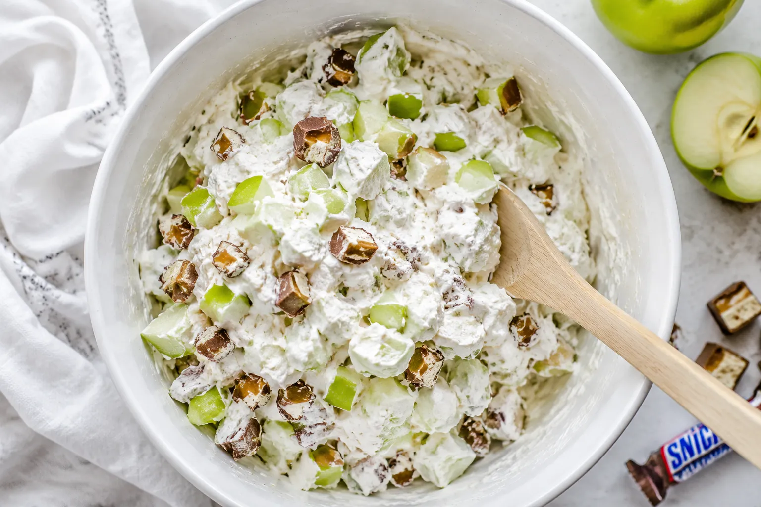 Folding apples and Snickers into creamy base for snickers salad recipe
