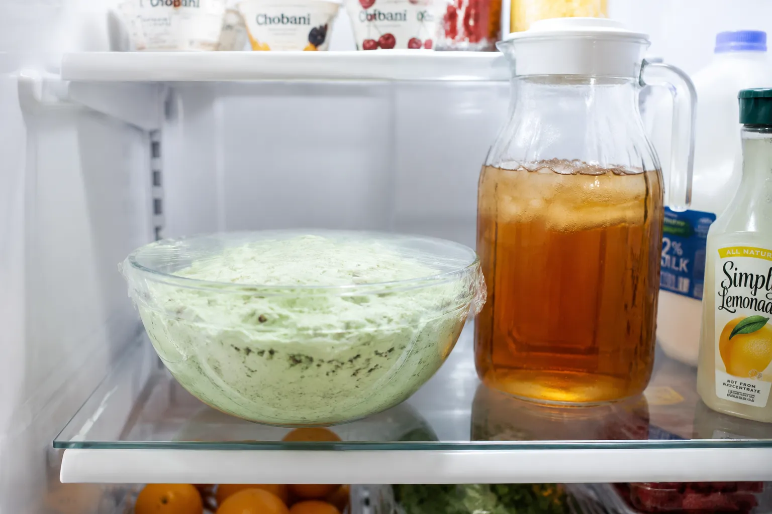 Pistachio salad covered in plastic wrap storing in the refrigerator