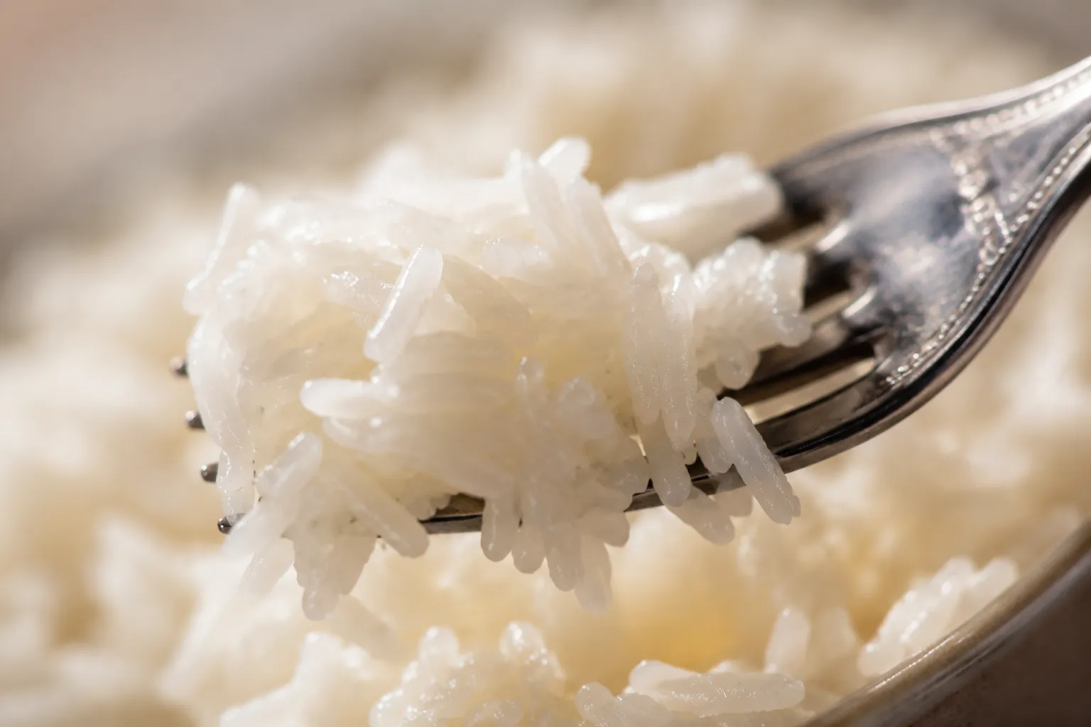 Fluffing cooked rice with a fork into separate tender grains