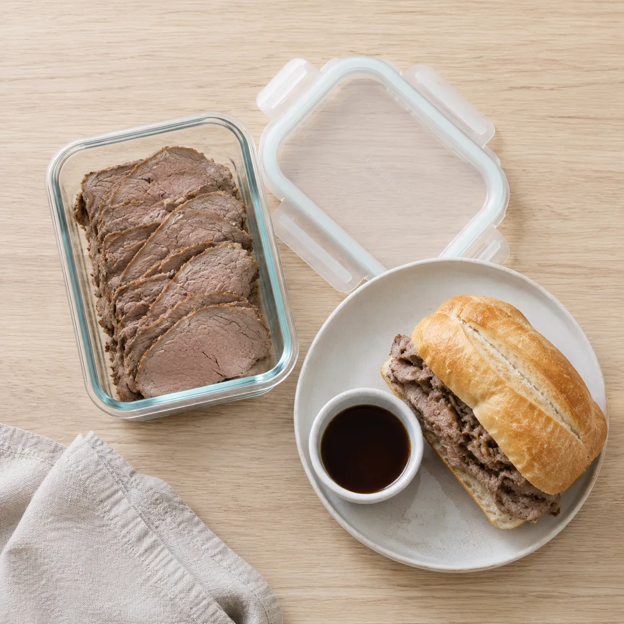 Leftover sirloin tip roast stored in glass container with French dip sandwich