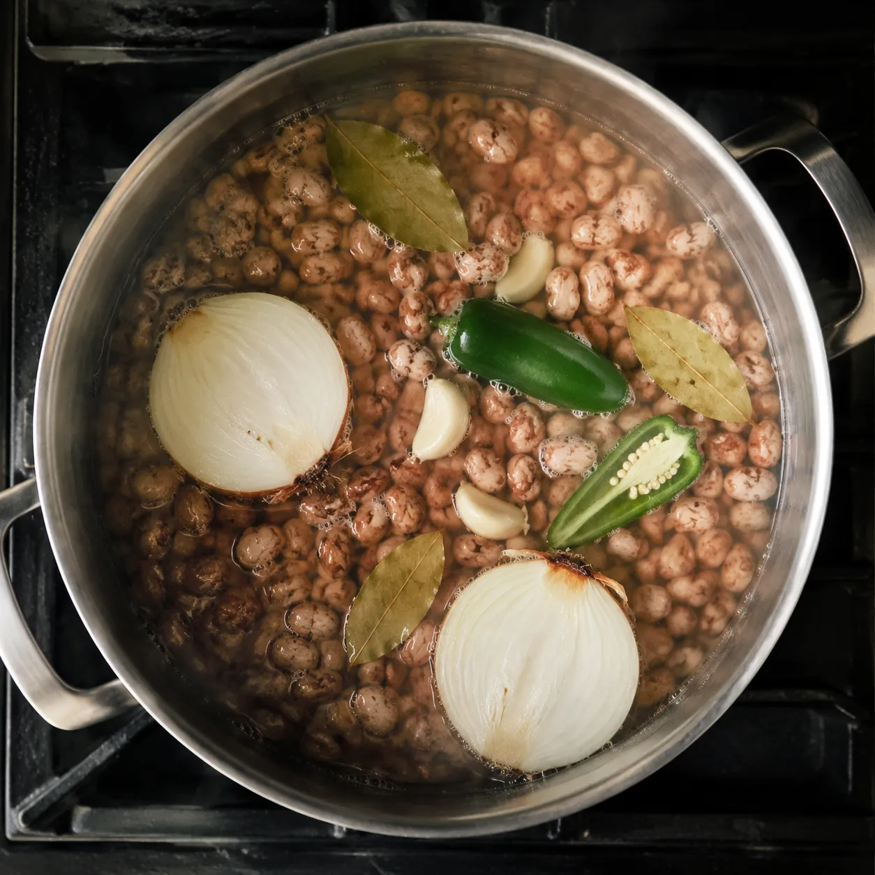 Pinto beans simmering with aromatics for authentic frijoles