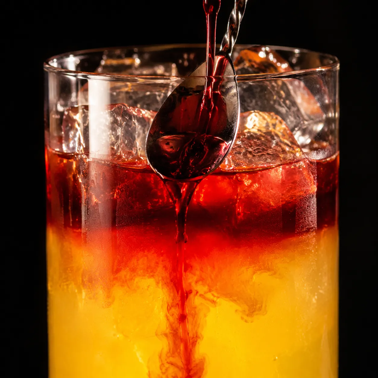 Floating cranberry juice to create a layered Malibu Bay Breeze cocktail