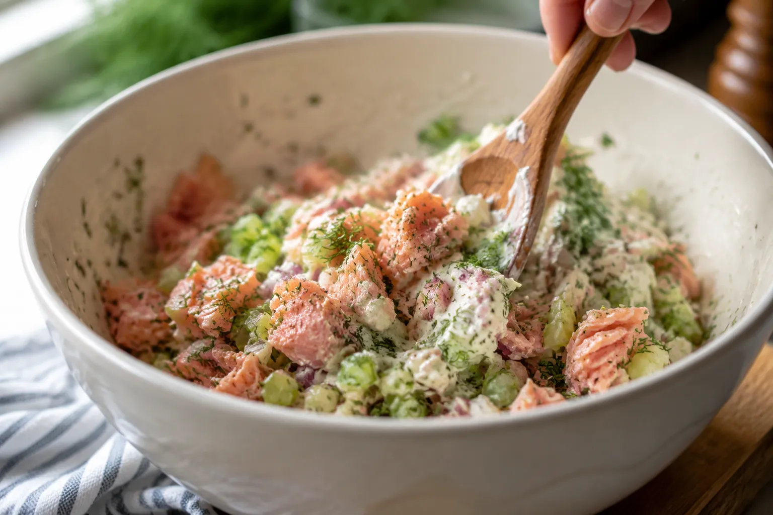 Mixing salmon salad recipe with celery, red onion, and fresh dill