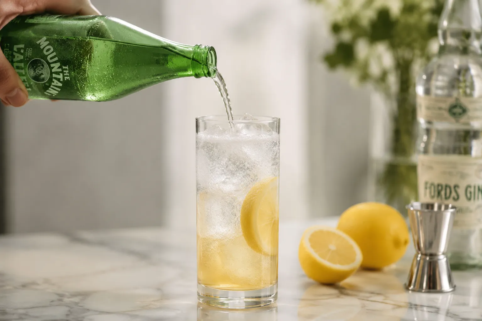 Topping a Tom Collins recipe with club soda in a Collins glass